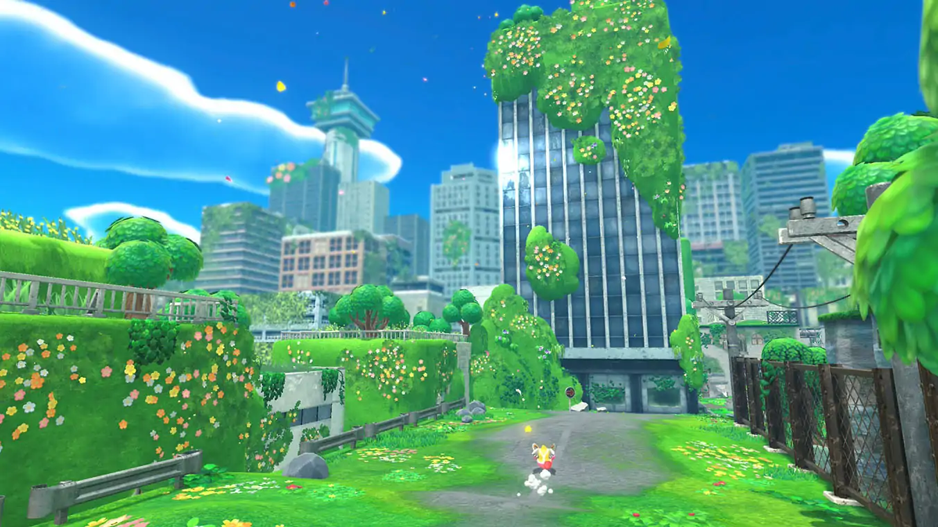 A gameplay screenshot showing Kirby from behind, running down an overgrown asphalt road. The road is surrounded by tiered green hills and an abandoned city of skyscrapers heavily covered in moss, vines, and blooming flowers under a bright sky.