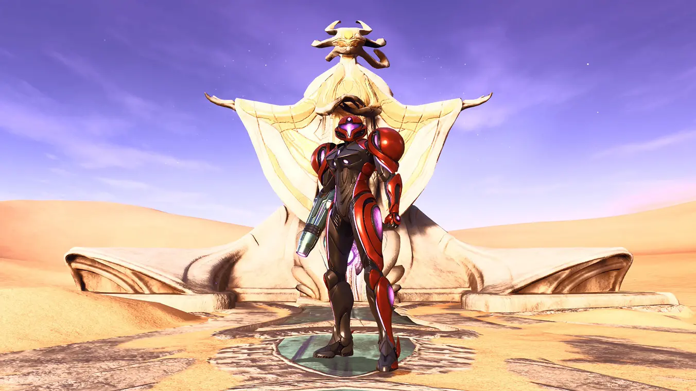 Third-person gameplay screenshot from Metroid Prime 4 showing Samus Aran in her sleek, red and black Varia Suit standing in a vast desert landscape. Behind her stands a massive, robed statue with outspread arms under a light purple sky.