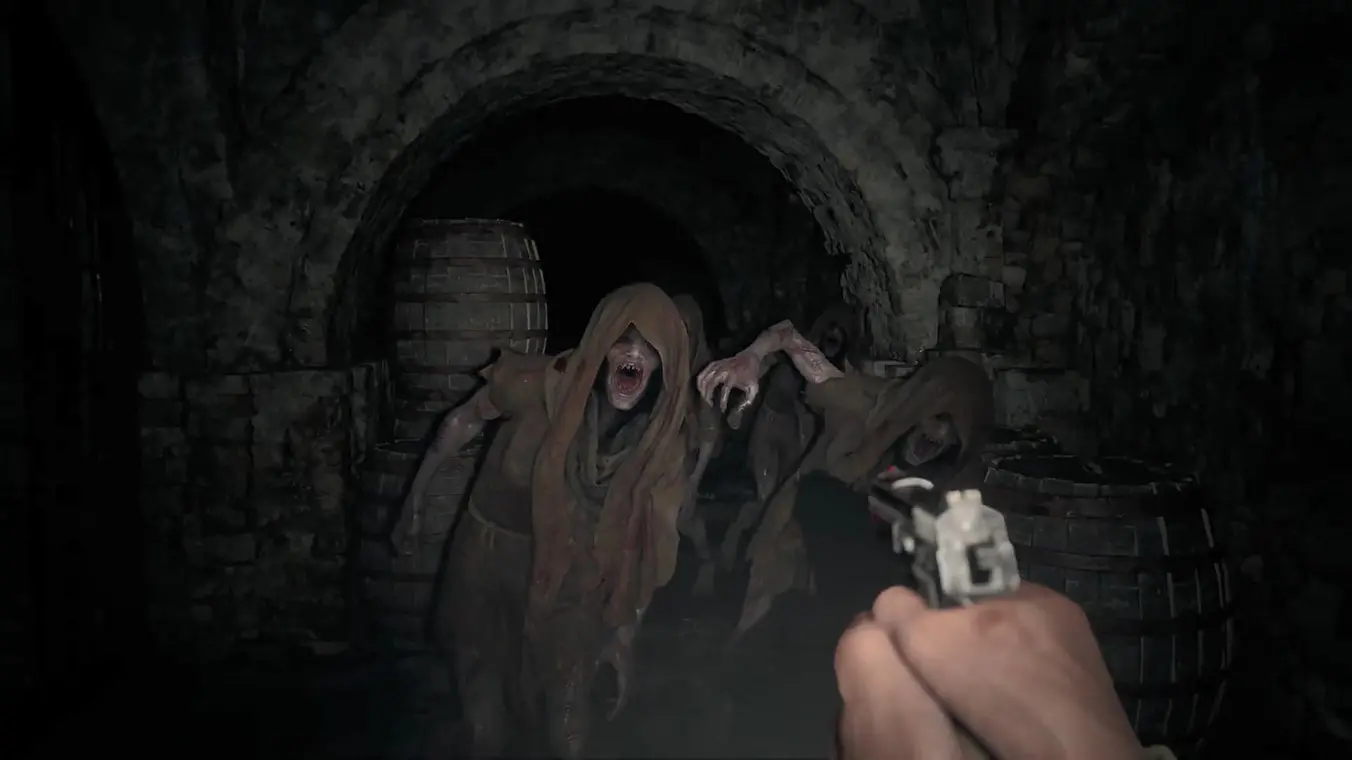 A first-person perspective gameplay screenshot inside a dark, stone dungeon tunnel. The player holds a handgun, aiming at several tattered, hooded ghoul-like enemies with open, fanged mouths rushing forward near wooden barrels.